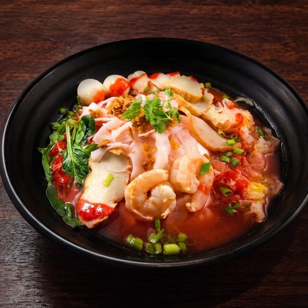 Yen Ta Fo, a Thai noodle soup with shrimp, fish balls, and vegetables in red broth.