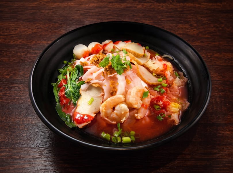 Yen Ta Fo, a Thai noodle soup with shrimp, fish balls, and vegetables in red broth.